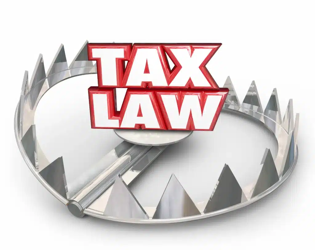 Tax Law words in red 3d letters on a bear trap illustrating irs misconceptions or legal trouble if you don't follow rules, regulations, guidelines or compliance standards in filing and paying taxes